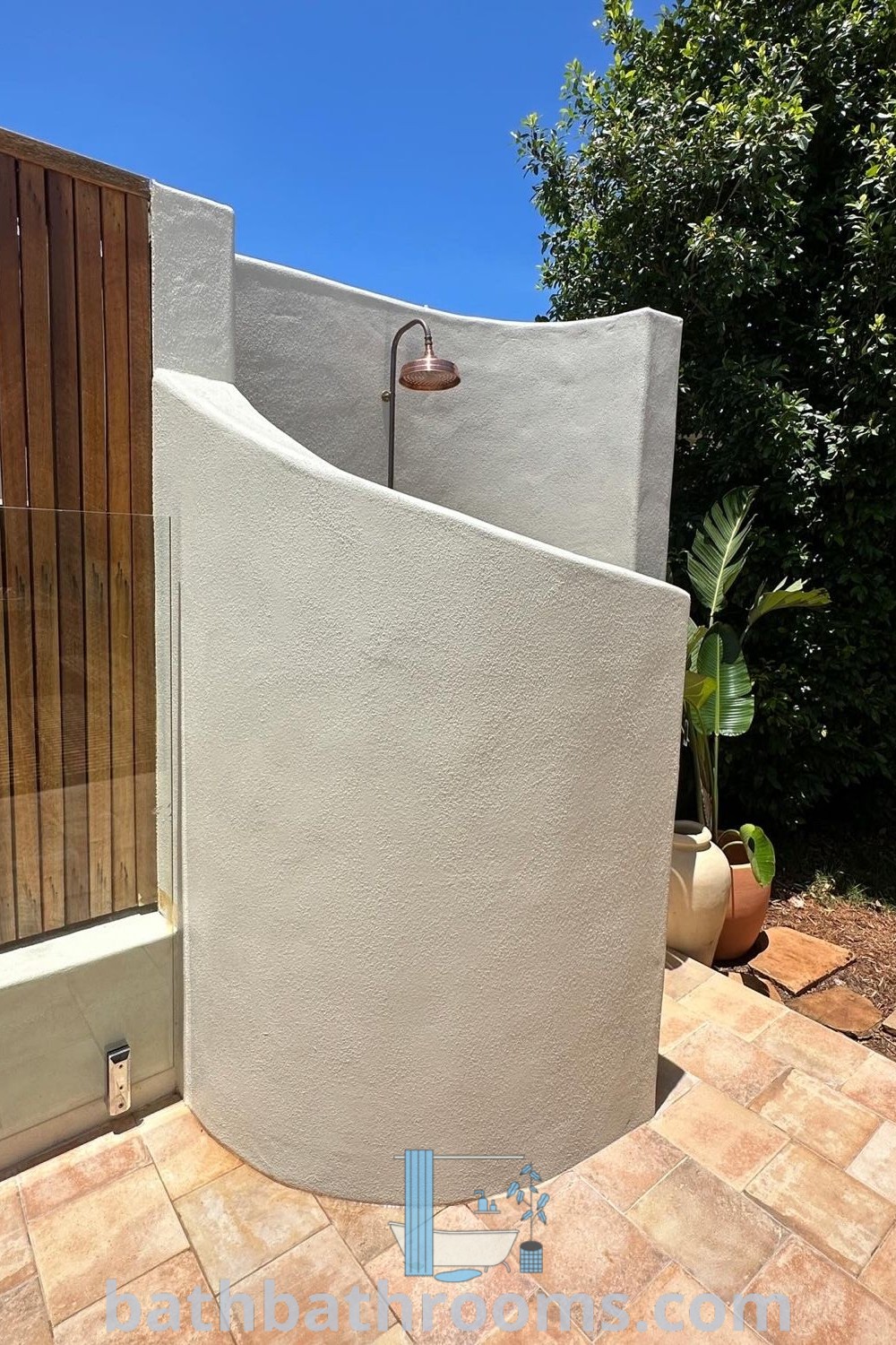 A beautiful outdoor shower in the corner of a patio, showcasing modern design elements ideal for backyards. This cozy and functional decor inspires with unique outdoor shower ideas, perfect for private spaces and enhancing your outdoor ambiance. Explore more at bathbathrooms.com.