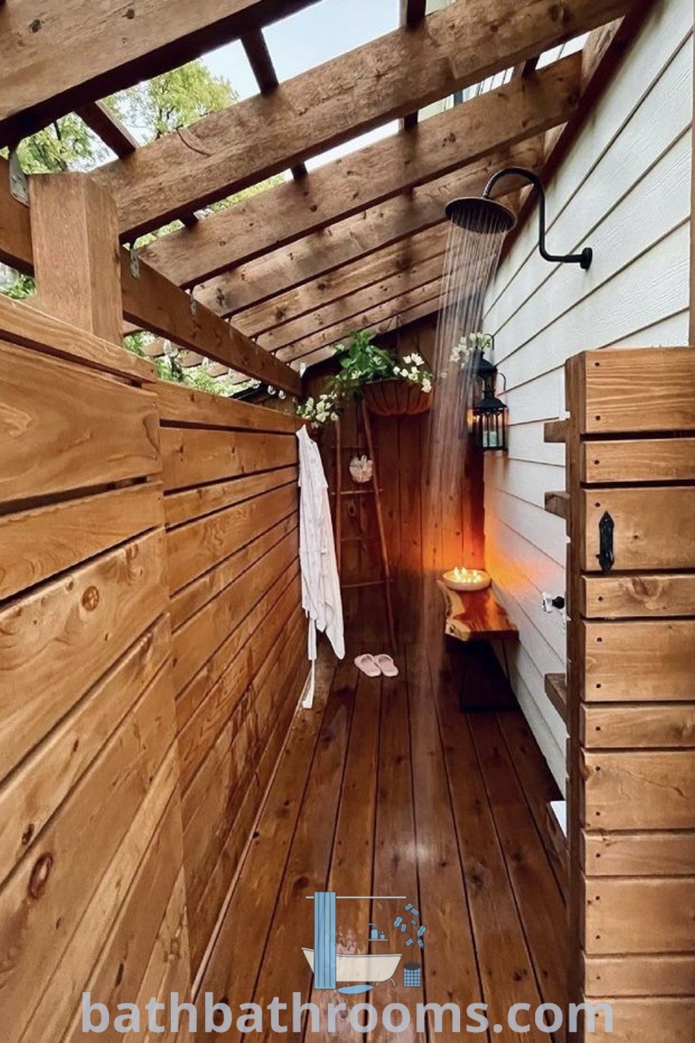 An outdoor shower in the middle of a wooden floored area with wood slats, featuring the best shower head and cozy design ideas. Explore outdoor shower enclosure inspirations and get ideas for your home at bathbathrooms.com.