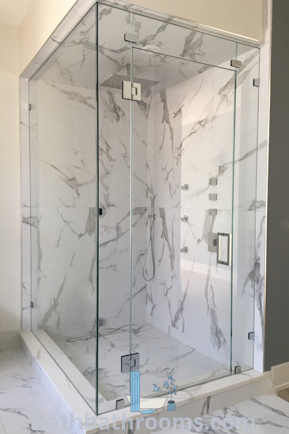 A modern glass shower stall in a bathroom with marble flooring and walls, accompanied by a white countertop, showcasing inspiring cubicle shower ideas and contemporary decor inspirations at bathbathrooms.com.