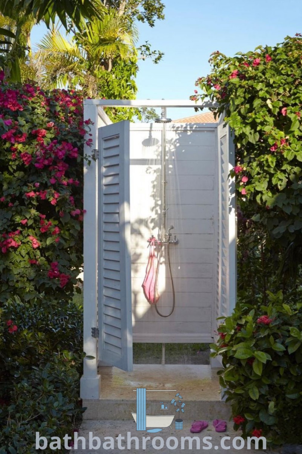 An outdoor shower design featuring an open white door leading into a vibrant garden filled with lush greenery and pink flowers. This cozy aesthetic showcases unique outdoor shower ideas and kits, perfect for enhancing your outdoor bathroom design. Discover more outdoor shower inspirations at bathbathrooms.com.