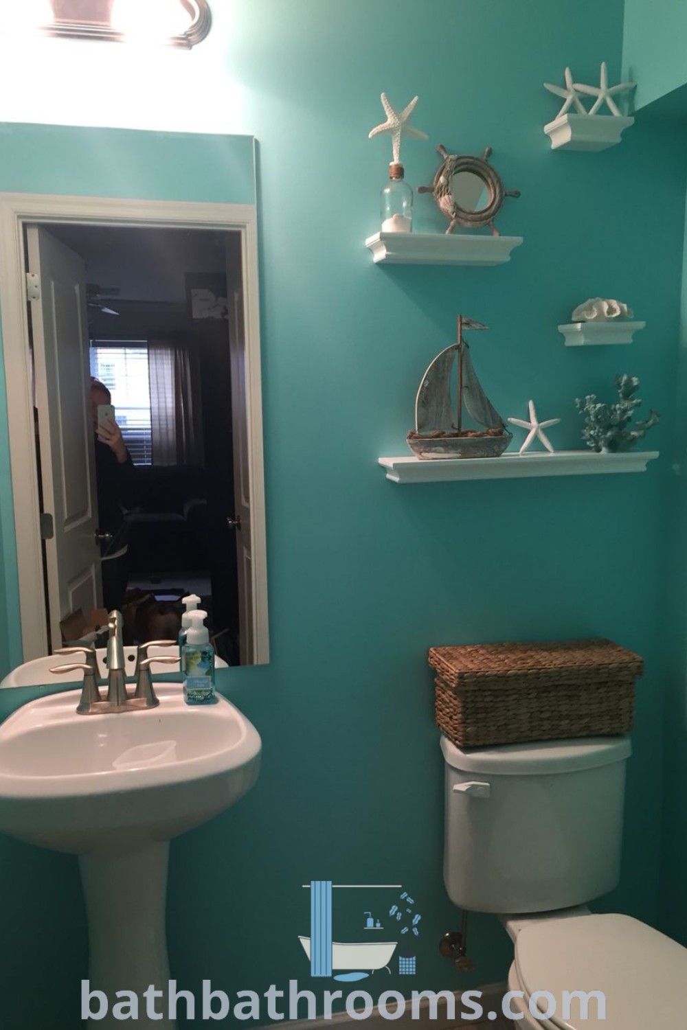 A small bathroom with blue walls and white fixtures, complemented by a wicker basket, showcasing aqua and brown decor. This coastal beach theme bathroom decor maximizes style and space, providing cozy and inspiring ideas for your home at bathbathrooms.com.