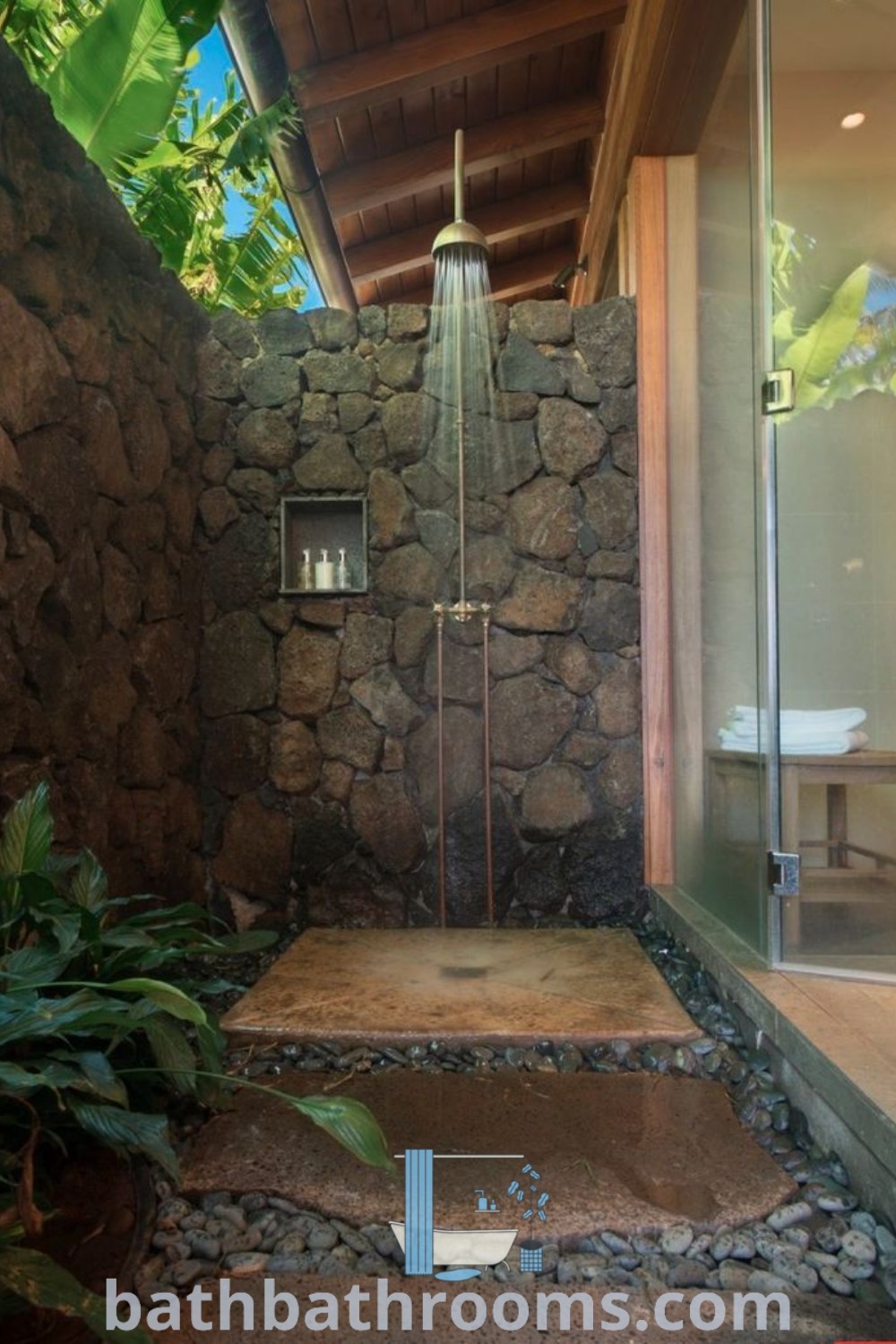 An outdoor shower integrated into a stone wall, complete with steps leading up to it, showcasing unique outdoor bathroom design ideas. This beautiful setup offers a cozy and inviting atmosphere, perfect for those seeking outdoor shower inspirations at bathbathrooms.com.