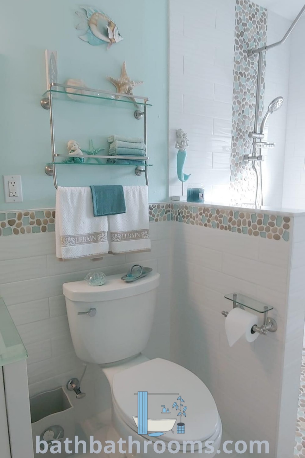 A coastal bathroom featuring a white toilet and sink, decorated in an ocean theme with seashell accents and teal elements. This beachy bathroom design offers inspiring decor ideas for a cozy home experience. Discover more at bathbathrooms.com.
