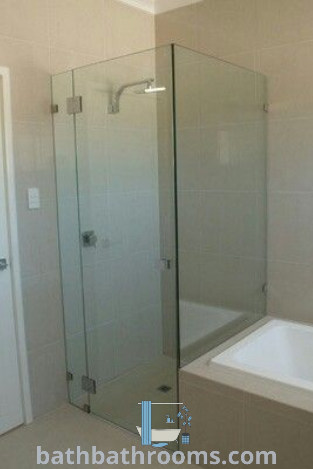 A stylish bathroom showcasing a semi-frameless shower screen next to a white bathtub and tiled walls, ideal for shower screen ideas and bathroom inspirations. Discover cozy design ideas and inspirations for your home at bathbathrooms.com.