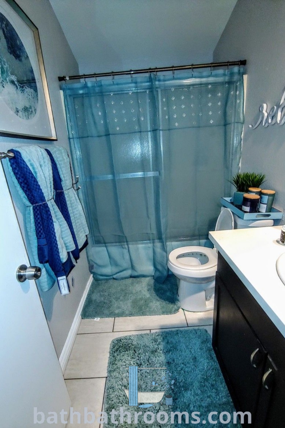 A stylish bathroom featuring a blue rug and shower curtain, showcasing cozy navy blue decor ideas. Perfect for those seeking inspiring color themes and practical decor inspirations for small spaces. Discover more at bathbathrooms.com.
