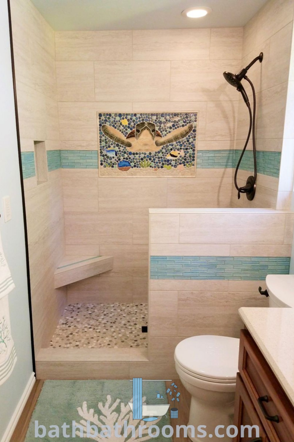 A beautifully designed bathroom with blue and white tiles on the shower wall, toilet, and sink area, featuring a sea turtle theme. Discover coastal shower tile and tub niche ideas that maximize style and space at bathbathrooms.com.