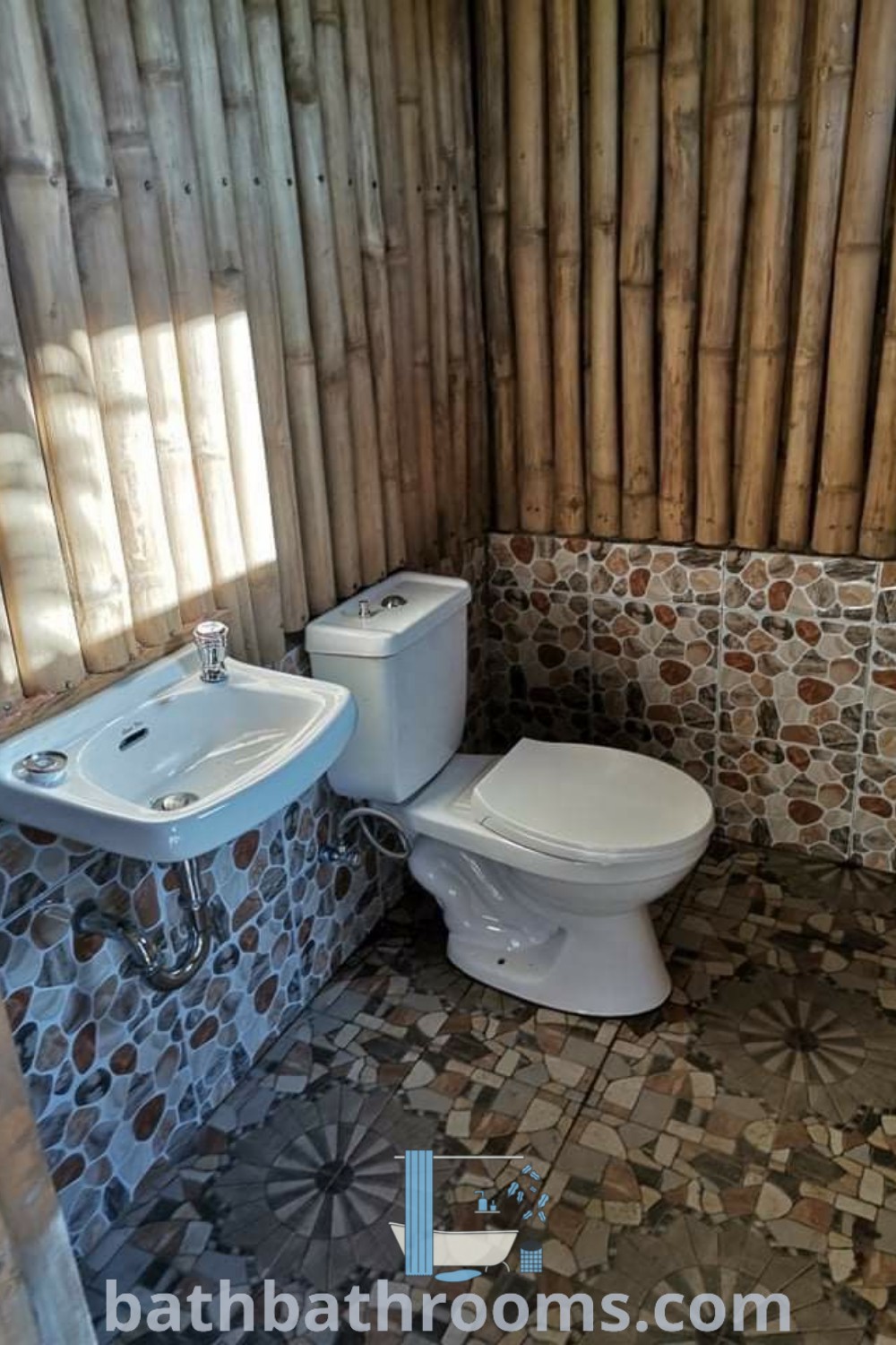 A cozy bathroom featuring a toilet and sink in a small room with bamboo wall panels. This design reflects bamboo bathroom ideas and outdoor toilet inspirations for a functional and serene aesthetic. Explore more decor ideas and inspirations at bathbathrooms.com.