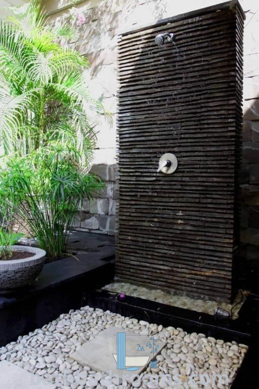 An outdoor shower in a backyard patio area next to a potted plant, demonstrating unique outdoor shower ideas and landscaping garden ideas. This design creates a cozy aesthetic while optimizing space for a refreshing bathing experience. Discover more decor ideas at bathbathrooms.com.