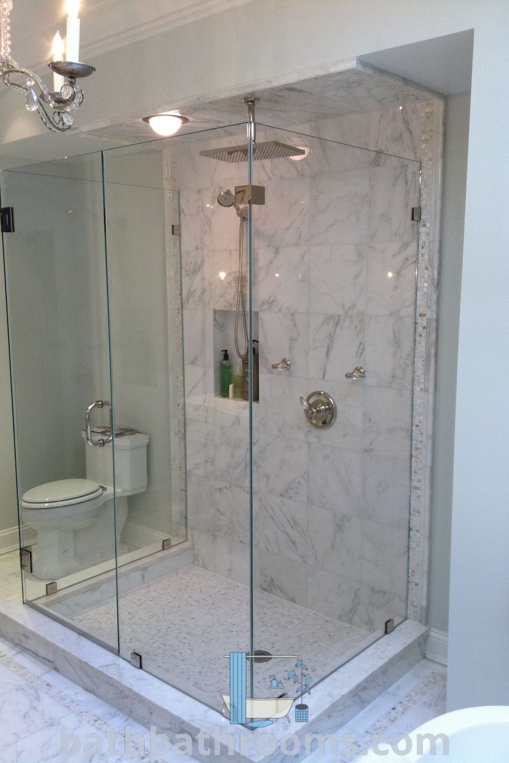 A bathroom featuring a walk-in shower with a 3-sided glass enclosure next to a white toilet and sink under a chandelier, showcasing unique design ideas. Explore more inspiring decor ideas at bathbathrooms.com.