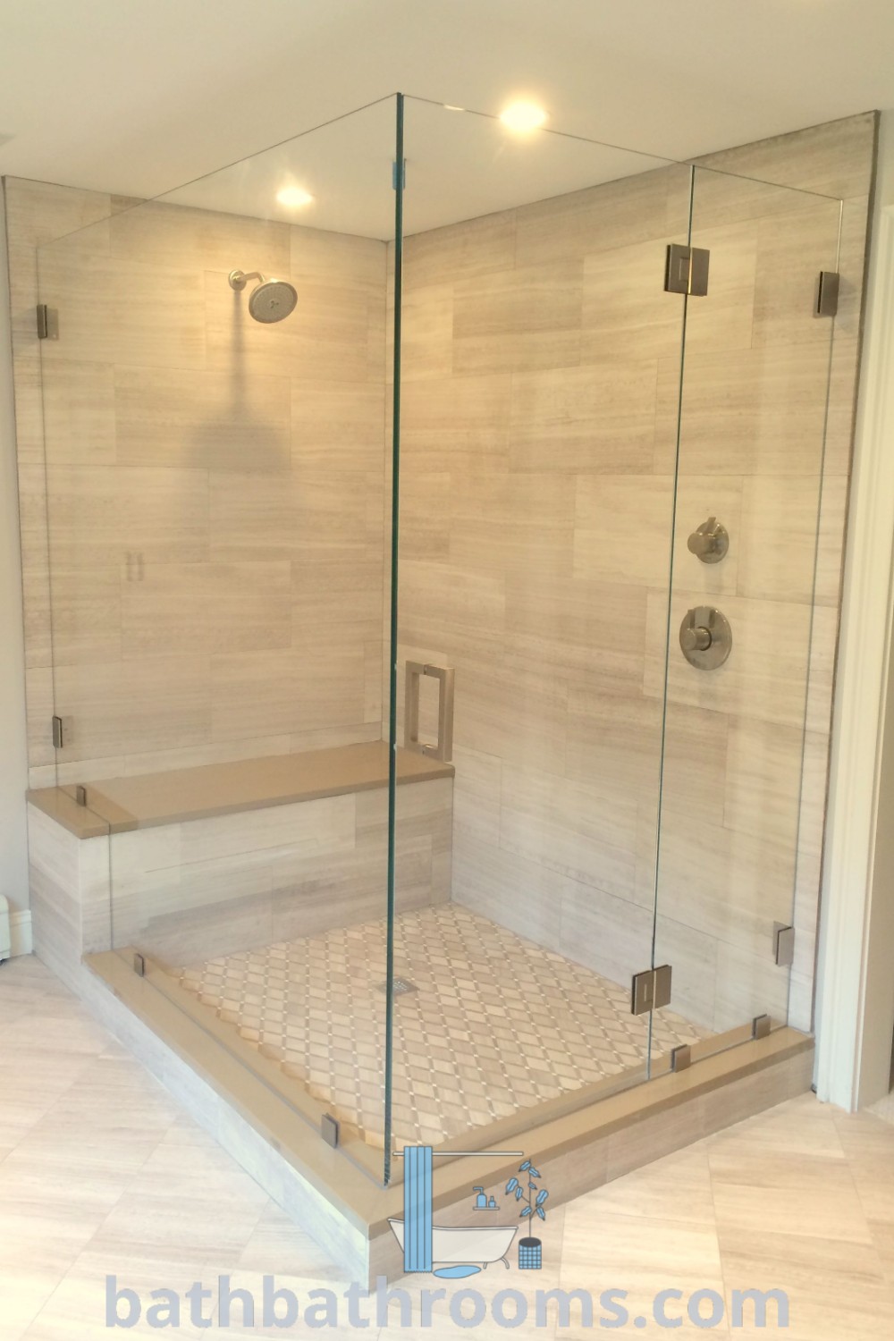A modern bathroom with a walk-in shower next to tiled floors and walls, featuring Dreamline shower doors and a stationary glass shower panel. This design offers a blend of style and functionality. Discover more design inspirations at bathbathrooms.com.
