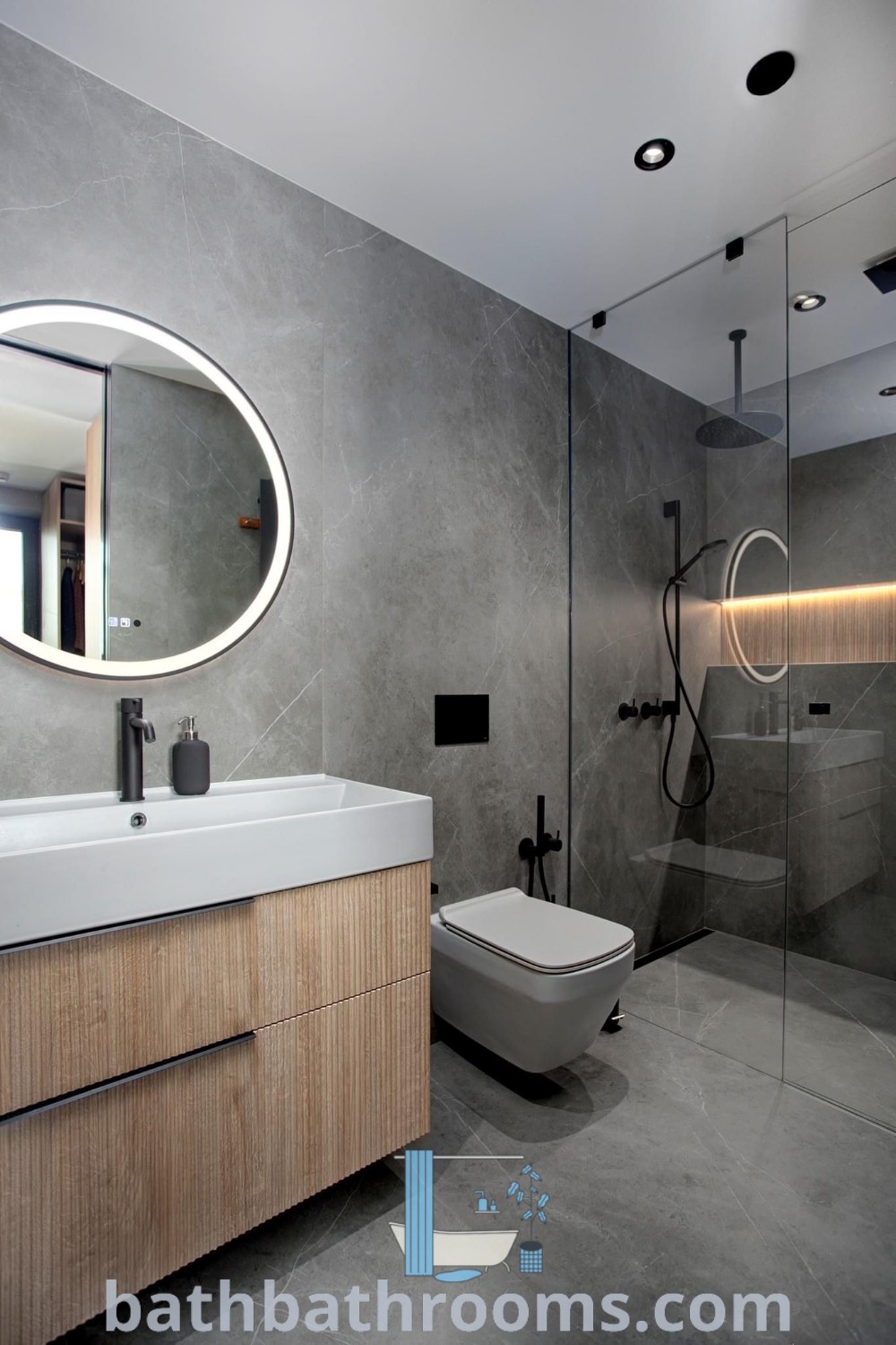 A modern grey bathroom with a sink, mirror, and toilet on the center wall, showcasing a cozy design with black accents and wood details. The space highlights grey bathroom ideas with functional decor inspirations. Find more unique bathroom design ideas at bathbathrooms.com.
