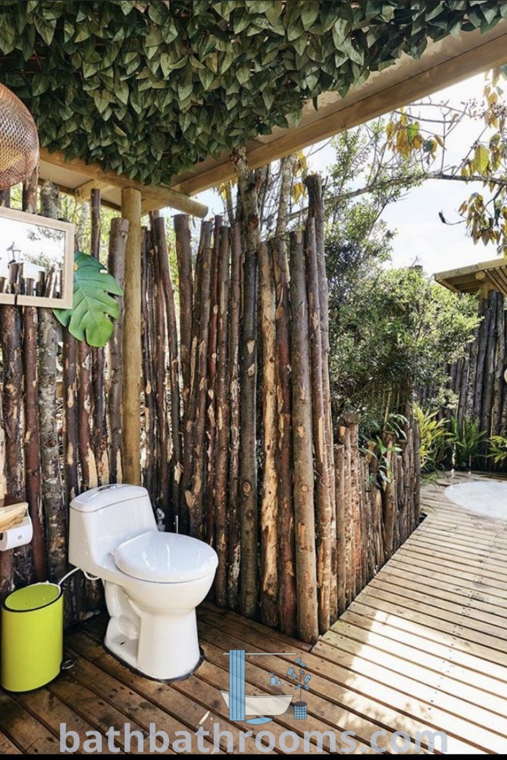 A tropical glamping bathroom with a toilet and sink in a small room featuring wooden flooring. The design showcases outdoor bathroom elements like a bamboo house and outside bathtub, creating a cozy aesthetic. Discover unique decor ideas and inspirations for small spaces at bathbathrooms.com.
