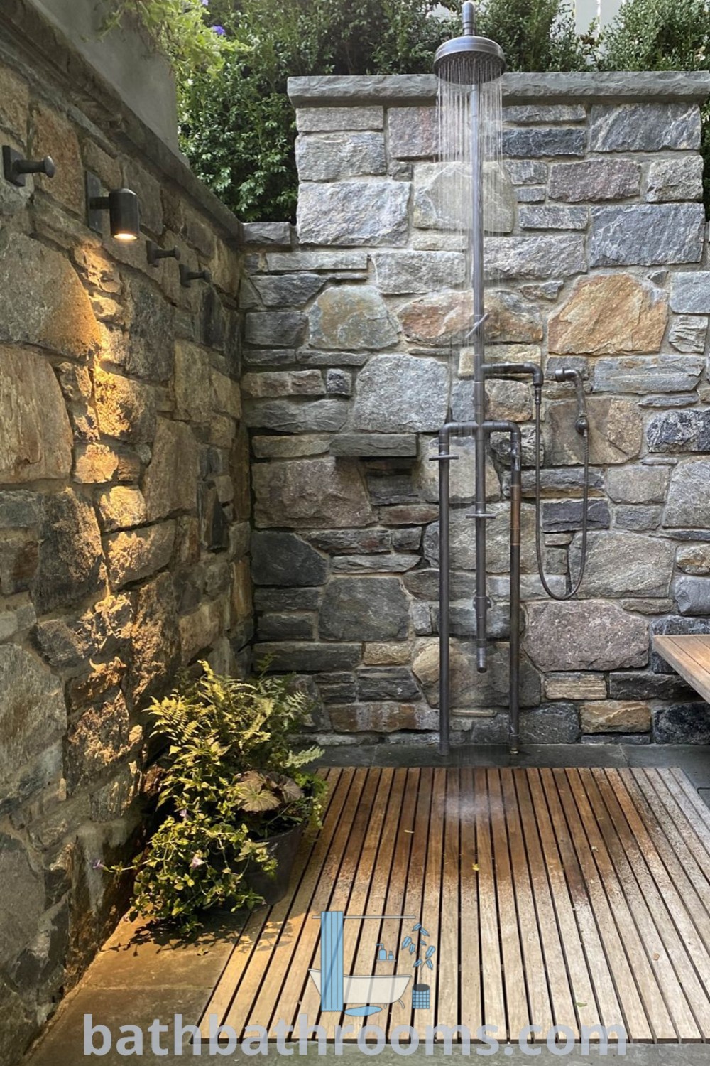 A beautiful outdoor shower featuring wood flooring and elegant stone walls, part of a magical environment in modern backyard landscaping. This design showcases outdoor bathroom ideas and inspires cozy aesthetics for your home. Visit bathbathrooms.com for more ideas!