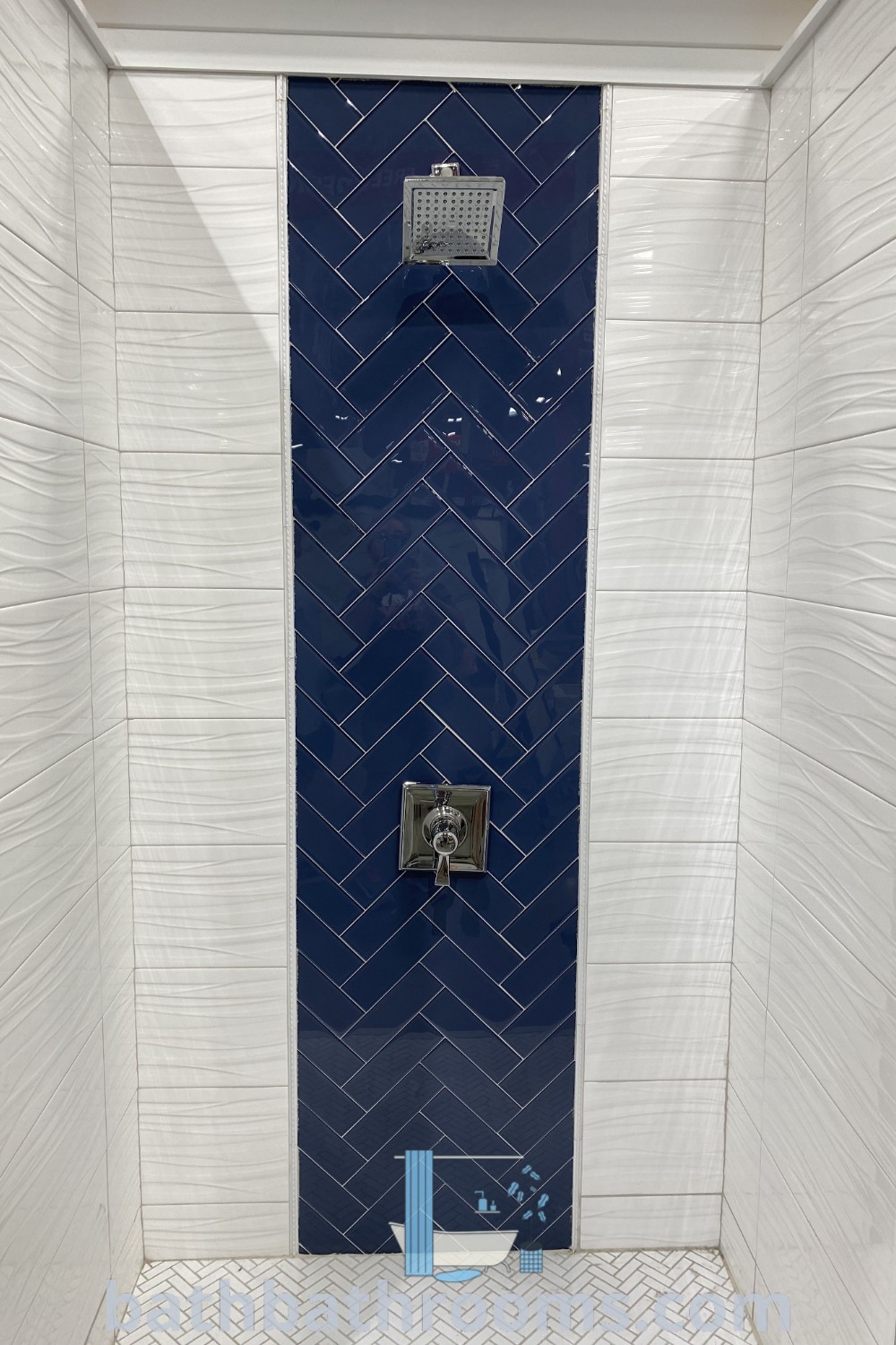A beautiful blue and white tiled shower stall featuring navy blue accent tiles against a white backdrop, showcasing unique shower tile ideas for bathrooms. Explore this inspiring decor and design ideas at bathbathrooms.com.