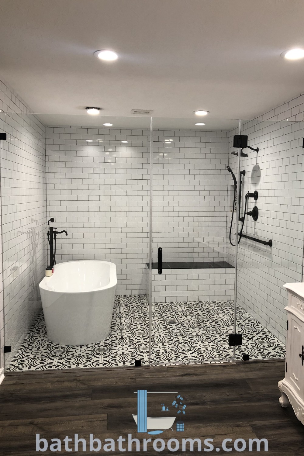 A white bath tub next to a walk-in shower in a stylish bathroom, showcasing design ideas for small spaces. This wet room concept combines the clawfoot tub and floor-level shower, ideal for bathroom remodel inspiration found at bathbathrooms.com.
