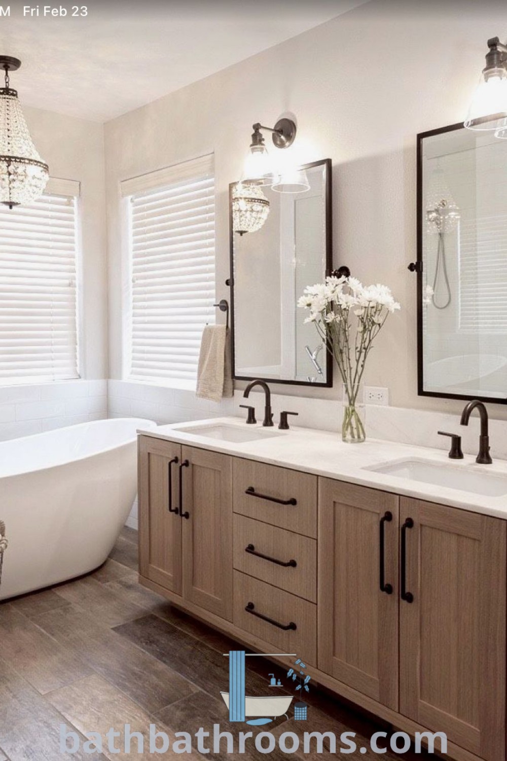 An aesthetic bathroom with double sinks, a bathtub, and a large mirror on the wall, showcasing beach-themed and French country farmhouse interior design elements. The cozy wood vanity complements the modern neutral home interior design, presenting inspiring decor ideas for your home at bathbathrooms.com.