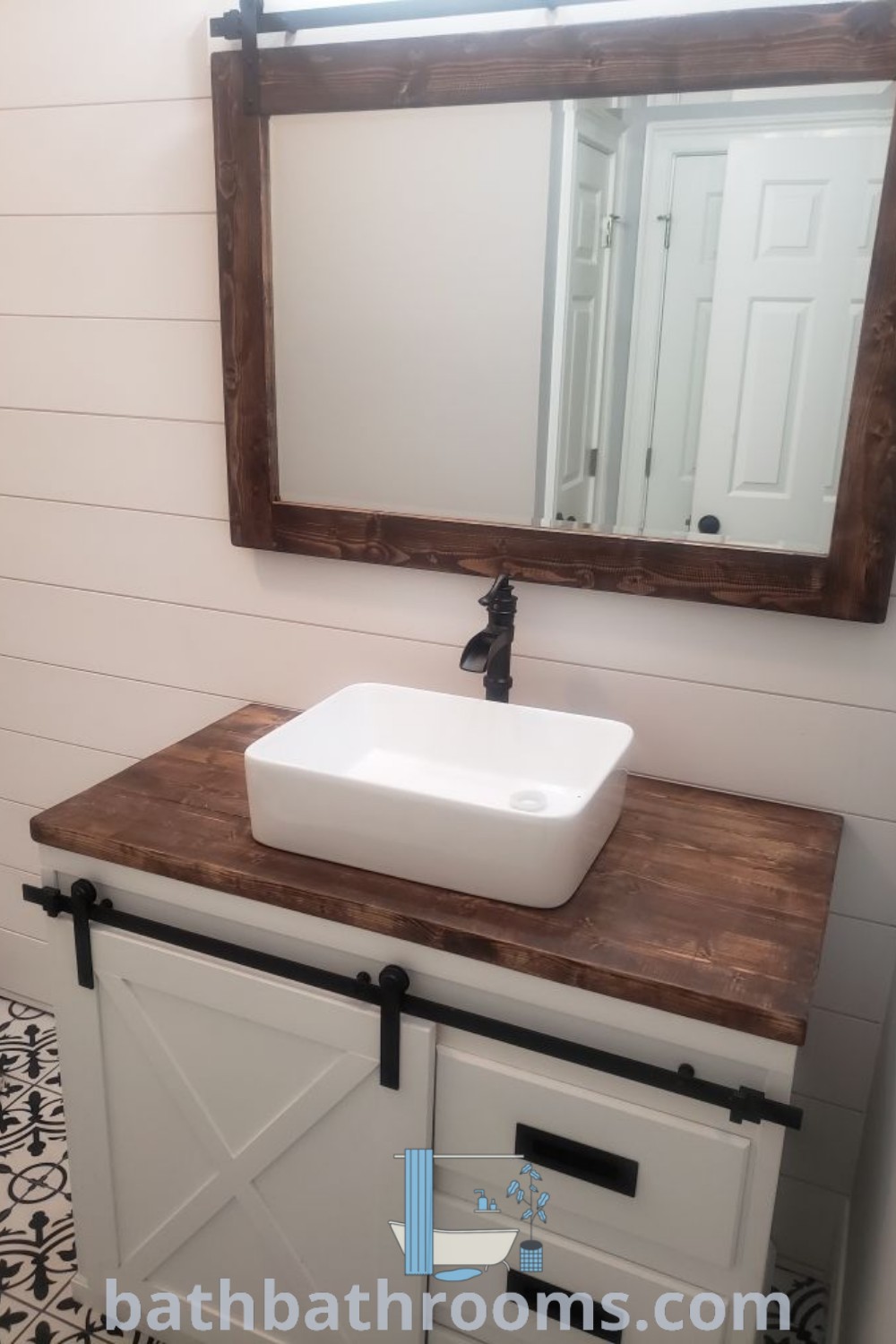 A cozy bathroom with a white sink on a wooden counter, a stylish mirror, and a black and white tile floor, offering rustic design ideas for small spaces. Explore more inspiring bathroom decor ideas at bathbathrooms.com.