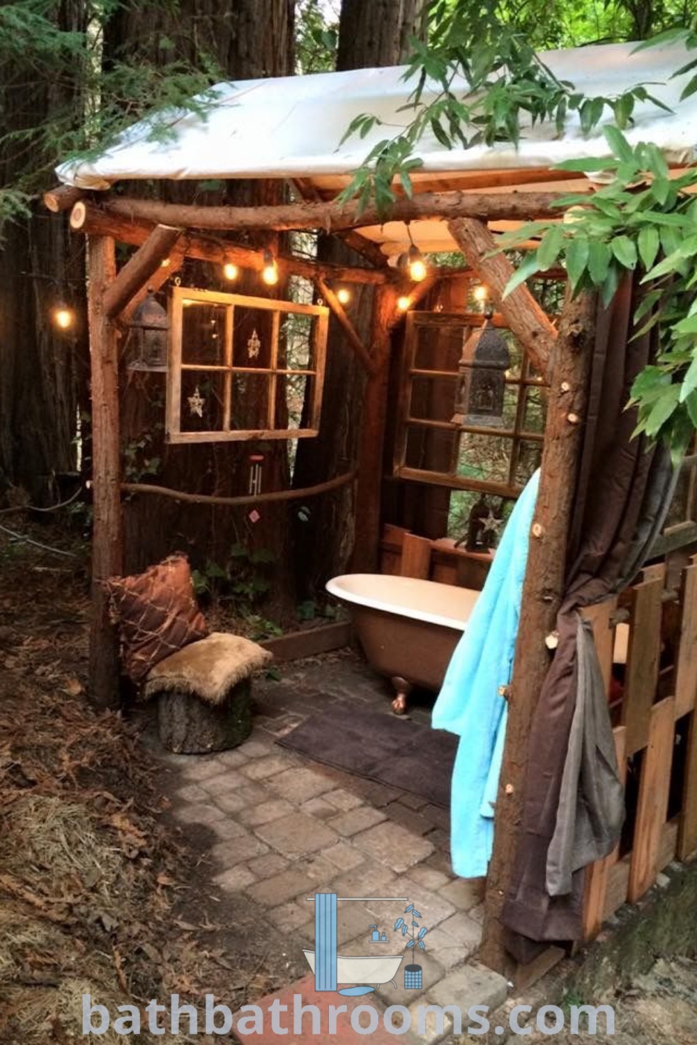 A cozy outdoor bathtub set in a wooded area, adorned with lights, showcasing rustic outdoor tub ideas like a bath house cabin and pallet shower outdoor. Discover more inspiring decor ideas at bathbathrooms.com.