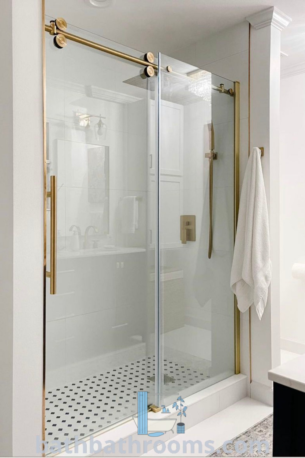 A bathroom featuring a walk-in shower next to a white countertop and a black and white tile floor, showcasing elegant gold glass shower doors. Discover inspiring design ideas and shower decor inspirations at bathbathrooms.com.
