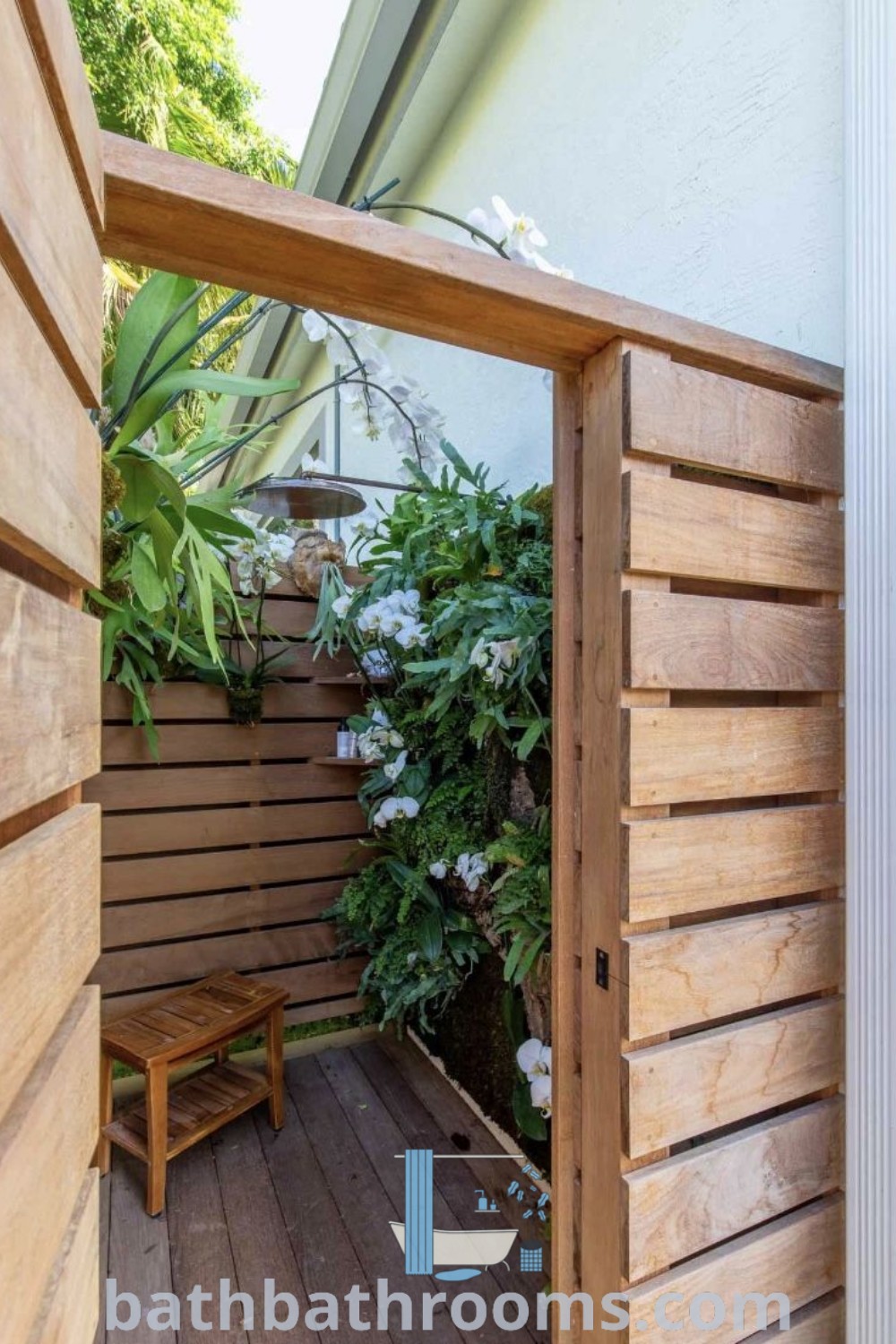 An open wooden door leading into a small garden featuring outdoor shower decor ideas suitable for tiny home backyard guest houses and boho aesthetics. Discover cozy inspirations and design ideas for outdoor shower enclosures at bathbathrooms.com.