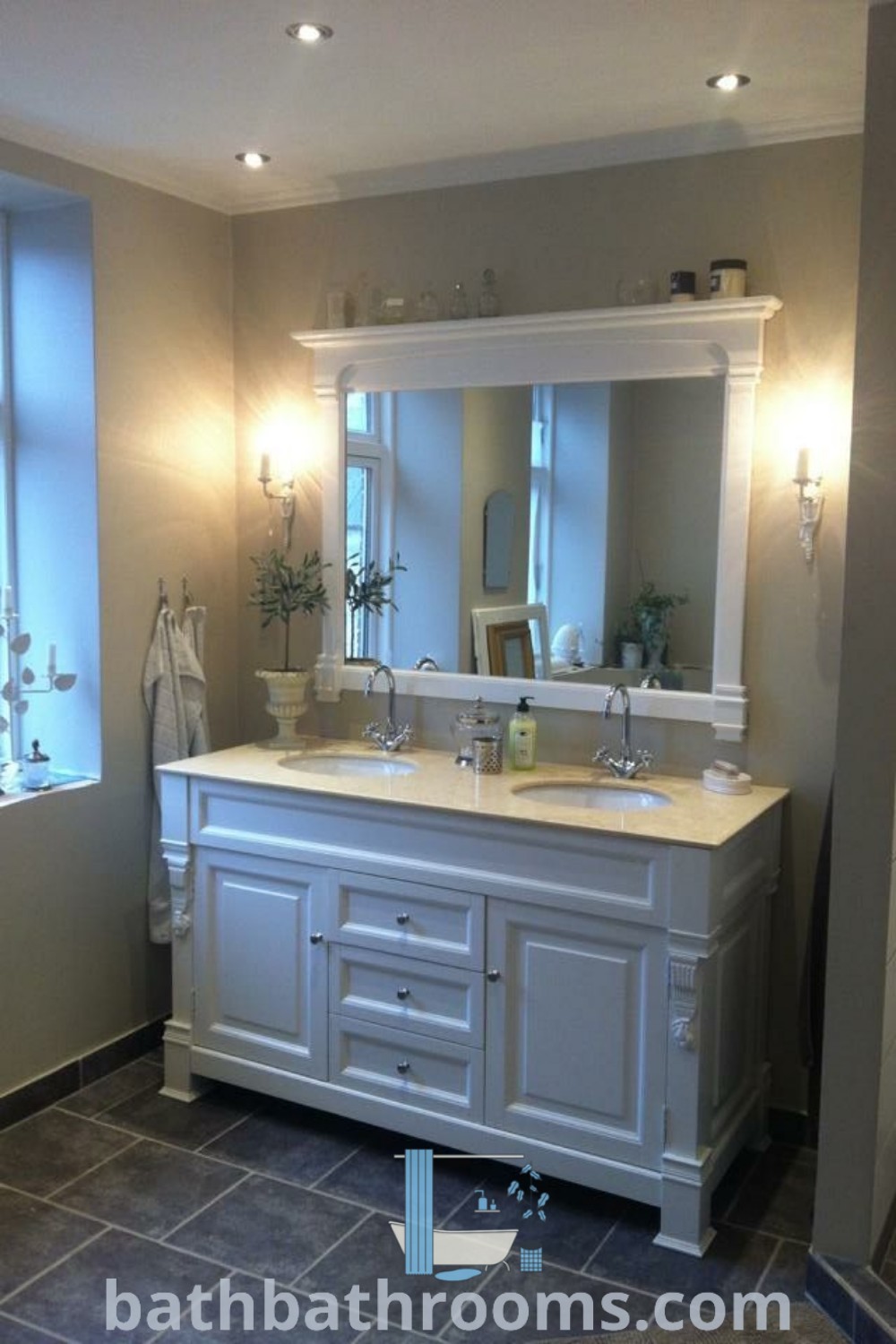 A charming bathroom featuring two sinks and a large mirror, designed in French country style that embodies cozy aesthetics and interior decor trends. Explore unique ideas and inspirations for decorating your home at bathbathrooms.com.
