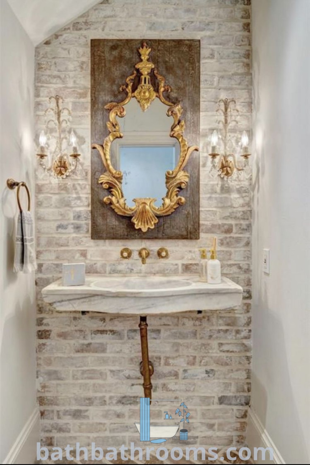 A stylish bathroom featuring a sink, mirror, and lights on a brick wall, decorated with gold accents, embodying French country farmhouse and shabby chic styles. Discover unique decor ideas for your home at bathbathrooms.com.