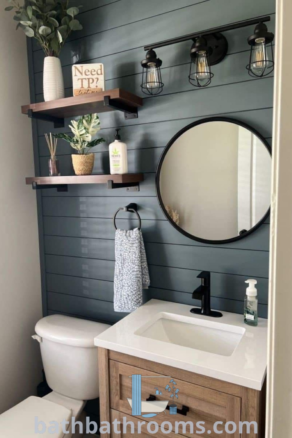 A small half bathroom showcasing a white toilet under a bathroom mirror, a wooden sink vanity, and stylish shelf decor. This design blends cozy aesthetic decor ideas with functional elements, creating an inviting space. Discover more inspirations at bathbathrooms.com.
