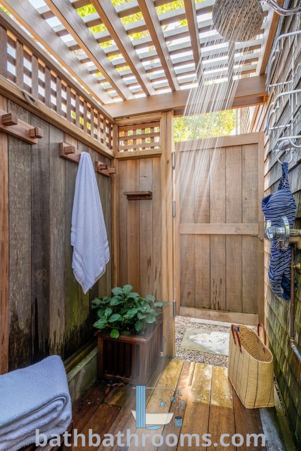 An outdoor shower with wooden walls and flooring next to a potted plant, exemplifying a cozy outdoor bath house style. This design inspiration highlights outdoor shower ideas for enhancing your backyard