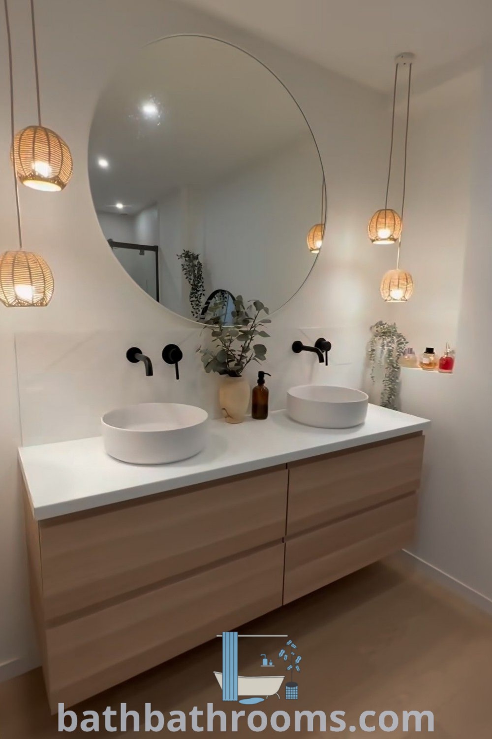 A stylish bathroom with two sinks, a round mirror, and hanging lights above the vanity, showcasing elegant bathroom lighting ideas for small spaces. This design offers cozy aesthetics and practical decor inspirations. Visit bathbathrooms.com for more unique ideas and tips for your home.