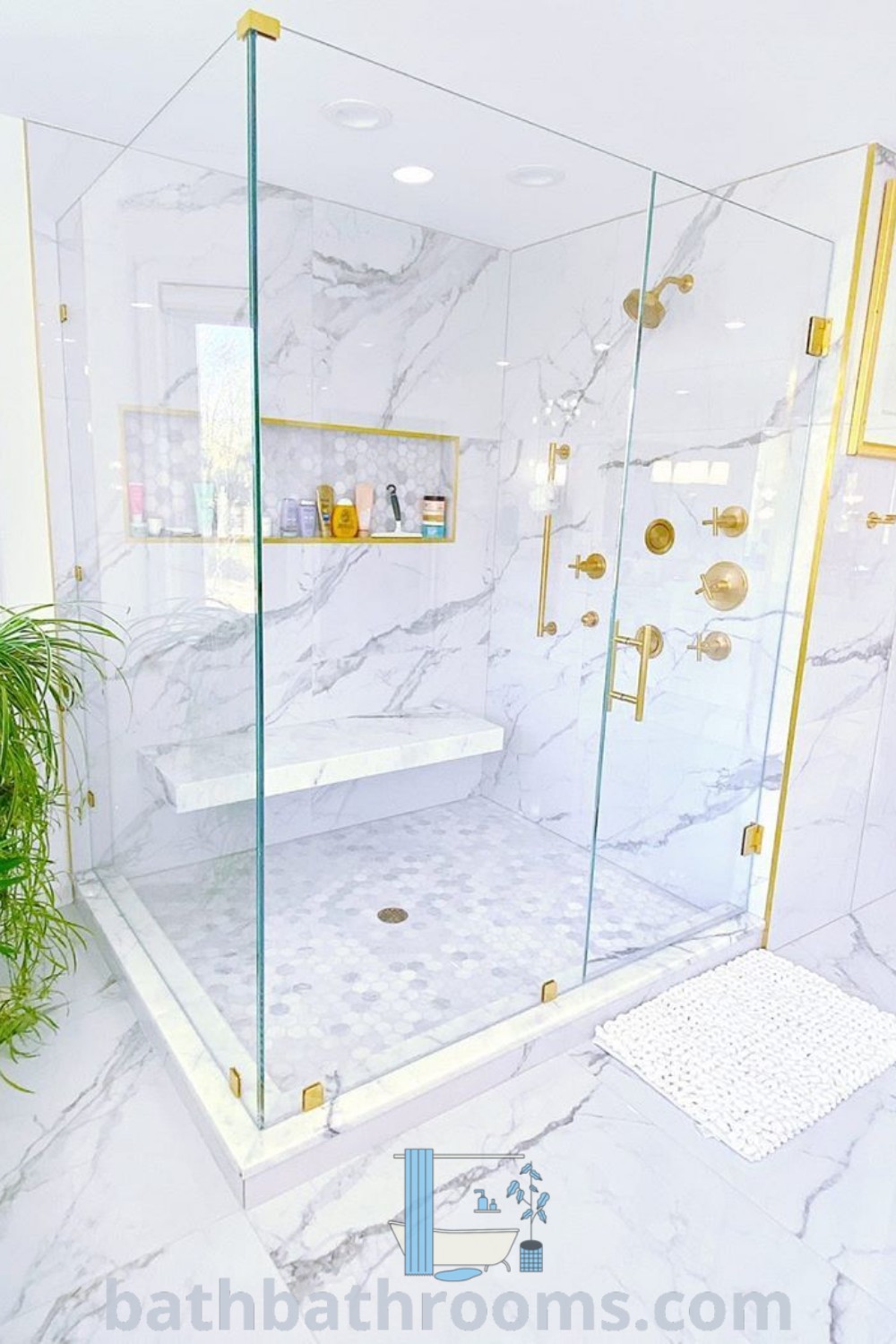 A modern bathroom showcasing marble walls and flooring with a walk-in frameless glass shower enclosure, adorned with gold shower doors and a plant for a cozy ambiance. Explore more inspiring decor ideas at bathbathrooms.com.