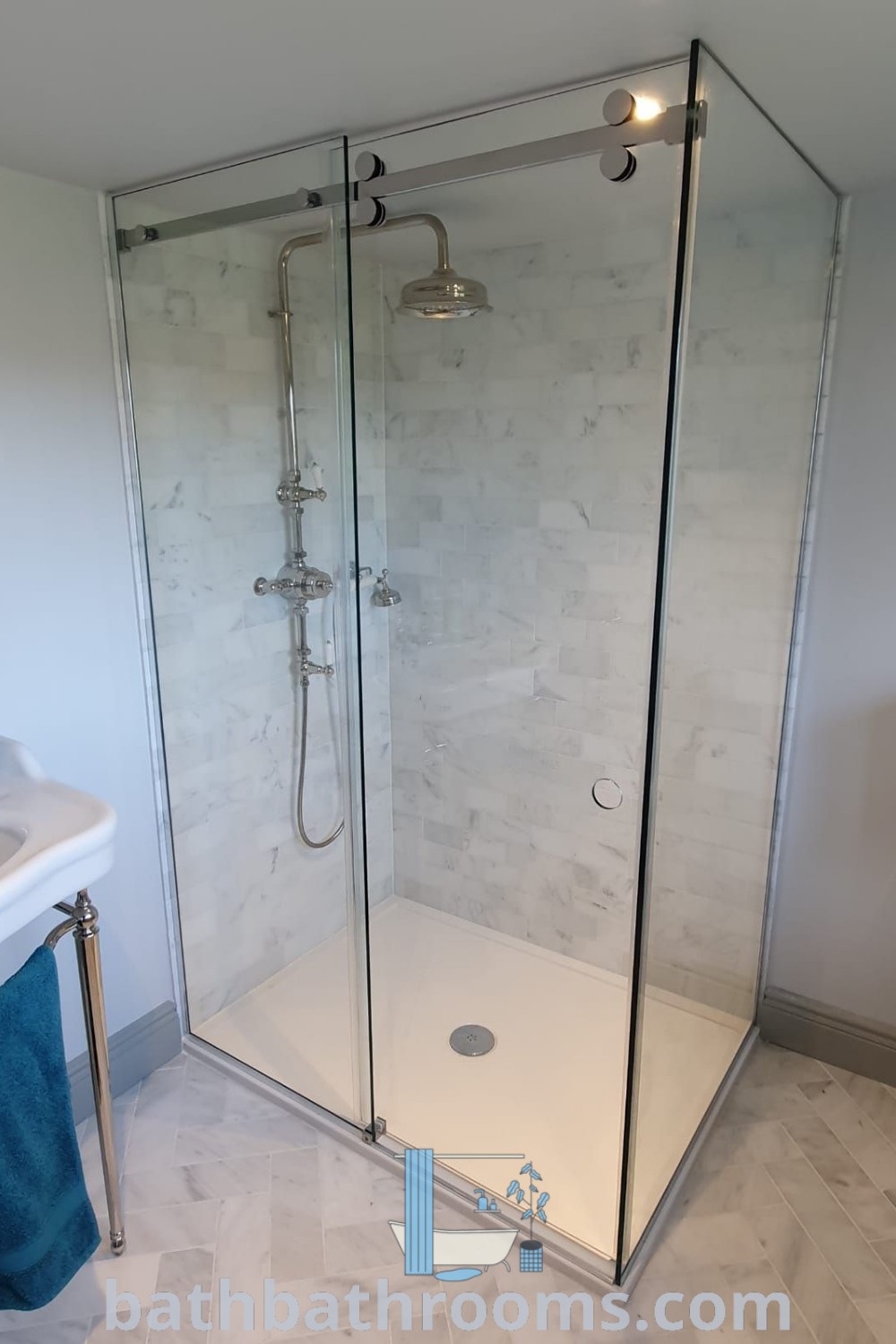 A frameless shower enclosure next to a white sink showcases modern design in a bathroom. Glass shower doors enhance the space, embodying luxury and style. Discover more inspiring decor ideas for your home at bathbathrooms.com.