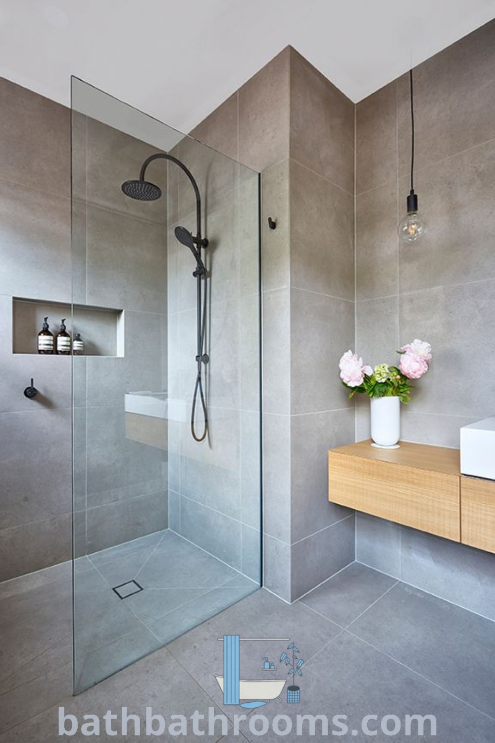 An elegant bathroom featuring a glass shower door, stylish sink, and flowers in a vase on the counter, showcasing shower panel ideas and luxury bathroom remodel designs. Explore more decor ideas for small spaces and inspirations at bathbathrooms.com.