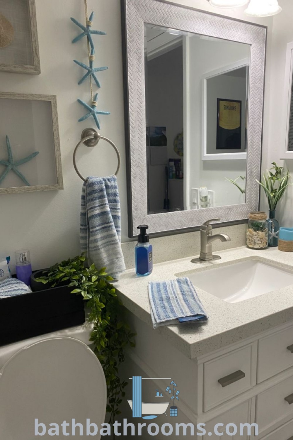 A cozy beach-themed bathroom featuring a sink, toilet, and mirror, decorated with simple blue ideas, seashell accents, and beach decor inspirations. Explore more unique decor ideas at bathbathrooms.com.