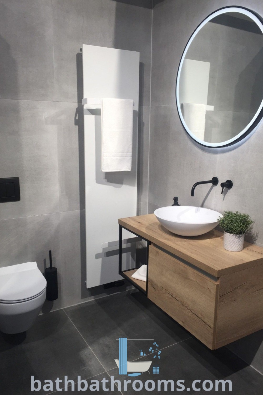 A modern small bathroom with a toilet, sink, and mirror in gray tones and stylish black and white accents. Discover bathroom color schemes gray and unique decor ideas for small spaces at bathbathrooms.com.
