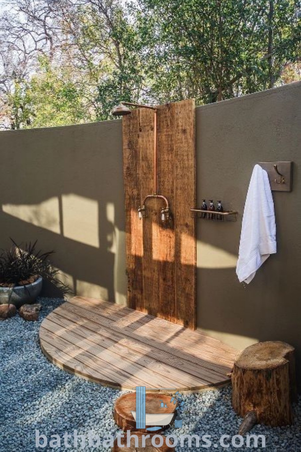 An outdoor shower set in the middle of a garden, showcasing a stylish design with ample greenery. This outdoor bathroom features unique ideas that merge functionality and decor, perfect for creating an inviting atmosphere. Discover more at bathbathrooms.com.