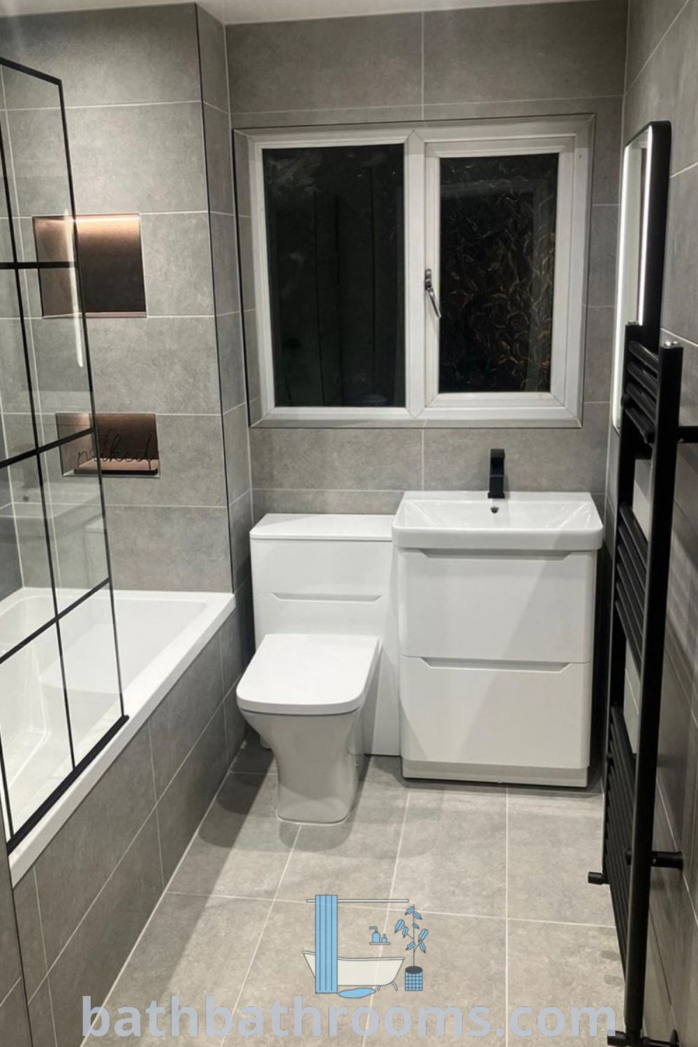 A modern UK bathroom featuring a white toilet, bath tub, and sink under a window, designed with grey tiles and cozy decor ideas. Discover inspirations and unique design ideas for small spaces at bathbathrooms.com.