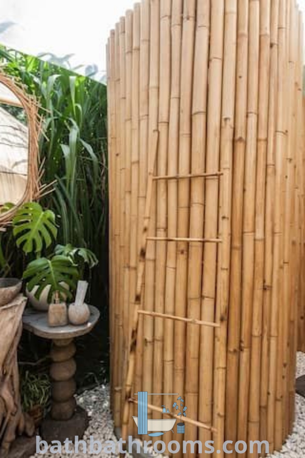 A beautiful bathroom featuring a bamboo shower, plants on the floor, and an oval mirror above, illustrating bamboo architecture and outdoor bathroom design concepts. Discover more inspiring bamboo bathroom decor ideas at bathbathrooms.com.