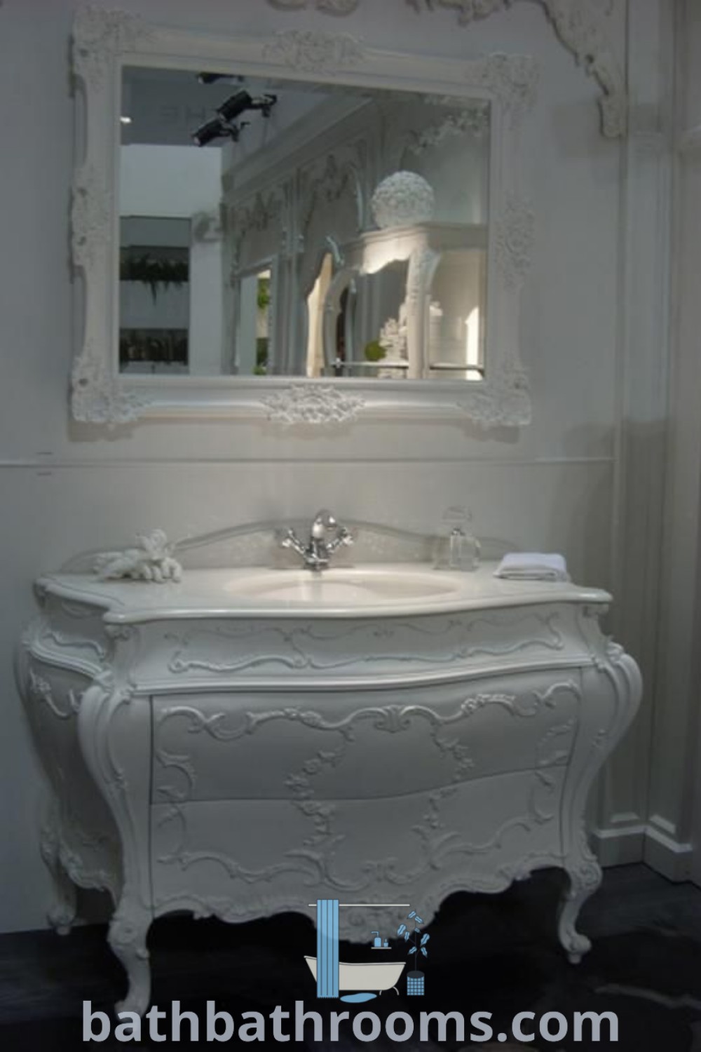 A white sink under a mirror in a bathroom, showcasing an elegant French Country bathroom vanity design. It embodies cozy decor inspirations and shabby chic elements, ideal for small spaces. Discover more inspiring designs at bathbathrooms.com.
