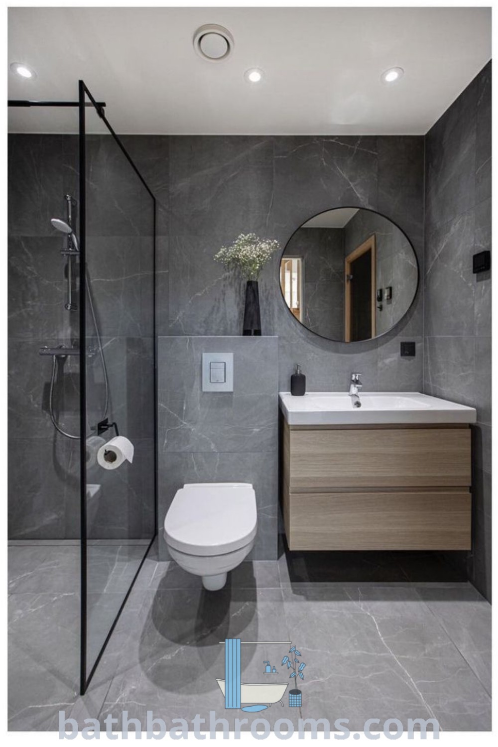 A modern bathroom with a grey marbled finish on the walls, featuring a toilet, sink, and shower stall. This design showcases the latest bathroom tiles and decor ideas, making it perfect for small spaces. Discover more bathroom inspirations at bathbathrooms.com.